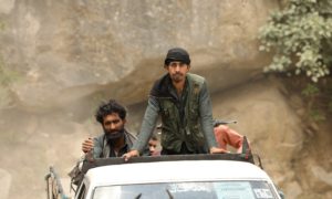 man in green jacket standing beside white car during daytime
