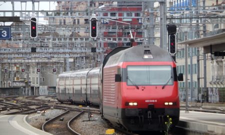 a red and silver train traveling down train tracks
