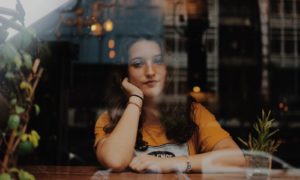 woman sitting next to table with hands on cheek