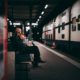 man in black jacket sitting on bench in train station