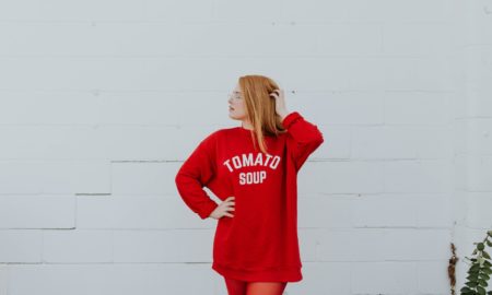 woman wearing red long-sleeved shirt standing near white painted wall