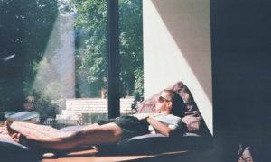 man lying on cushion beside glass window
